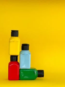 Bottles with bright multi-colored acrylic paint on a yellow background Stock Photos