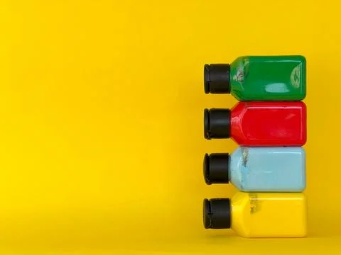 Bottles with bright multi-colored acrylic paint on a yellow background Stock-Fotos