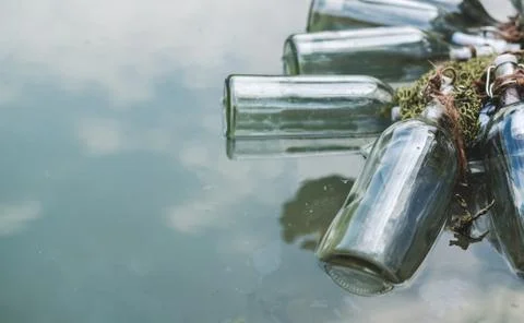 Bottles connected with notes inside float by the lake. Quests, games, adventures Stock Photos