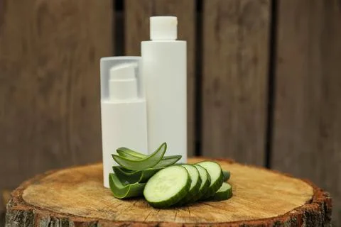 Bottles of cosmetic products, sliced aloe vera leaves and cucumber on wooden  Stock Photos