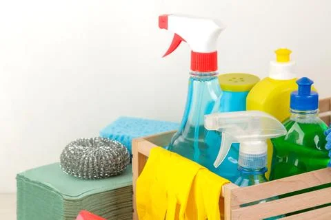 Bottles with detergent and cleaning tools in a drawer on a light background. Stock Photos