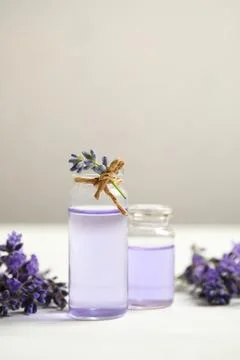 Bottles of essential oil and lavender flowers on white wooden table Stock Photos