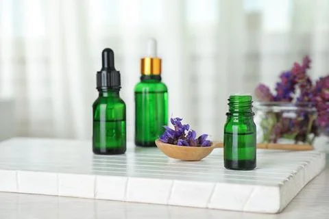 Bottles of essential oil and sage flowers on table, space for text Stock Photos