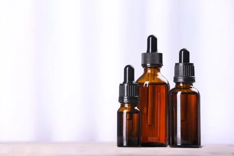 Bottles of essential oils on table against light background, space for text.  Stock Photos