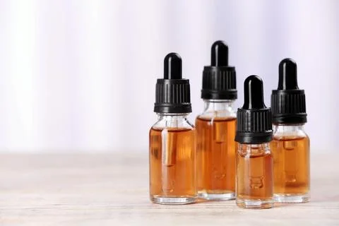 Bottles of essential oils on table against light background, space for text.  Stock Photos