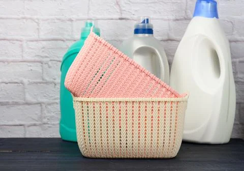 Bottles with liquid detergent and plastic empty laundry baskets on a wooden.. Foto stock
