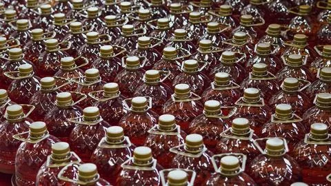 Bottles of red liquid arranged in rows on a production line Stock Photos