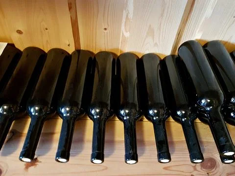 Bottles of red wine without rustic labels on a wooden rack Stock Photos