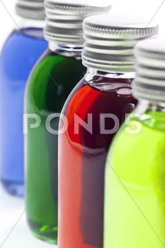 Bottles in a row with different colored liquid Stock Photos