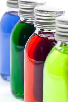 Bottles in a row with different colored liquid Photos