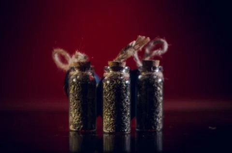 Bottles with spices stand in the mirror surface on a red background Stock Photos