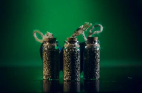 Bottles with spices stand in the mirror surface on a green background Stock Photos