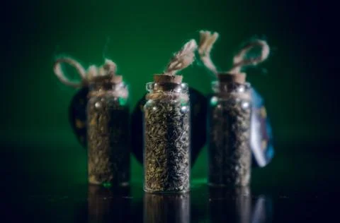 Bottles with spices stand in the mirror surface on a green background Stock Photos
