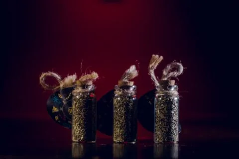Bottles with spices stand in the mirror surface on a red background Stock Photos
