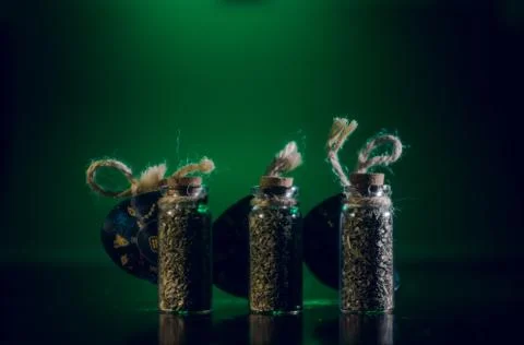 Bottles with spices stand in the mirror surface on a green background Stock Photos