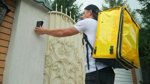 Bottom angle view of confident courier ringing door bell on gate standing Stock Footage 202637596