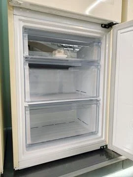 Bottom freezer section of a big beige refrigerator with open door, perfect .. Stockfoto's
