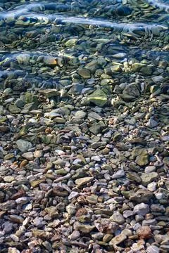 Bottom full of pebbles through the clear transparent water of the sea Stock Photos