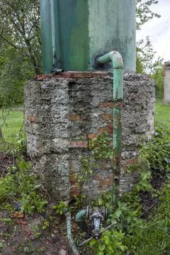 A bottom part of water tower with rusty valve and pipes Stock Photos
