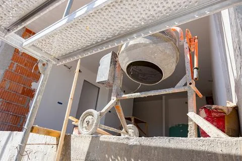 Bottom shot on mortar mixer machine on the terrace of unfinished edifice Stock Photos