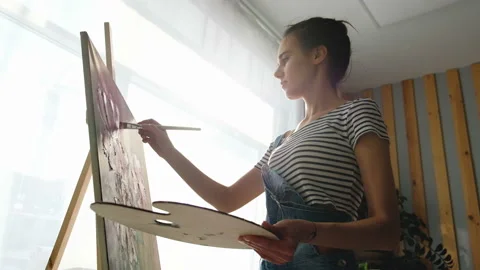 Bottom side view of a charming young woman artist paints a watercolor painting Stock Footage 111032800