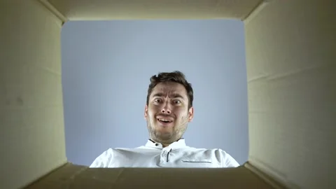 Bottom view, Amazed man looks into the empty box from the inside Stock Footage 134466671