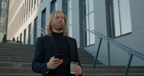 Bottom view of bearded man with coffee paper cup smiling while using mobilephone Stock Footage 143144941