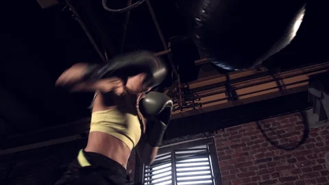 Bottom view from below young pretty girl athlete is boxing with a punching bag Stock Footage 112919529
