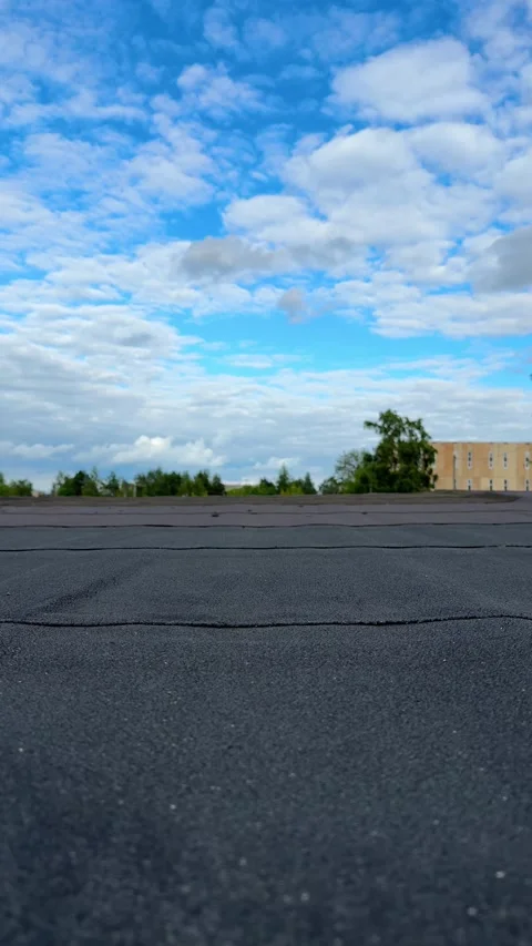 Bottom view of black bitumen membrane of flat roof under blue cloudy sky Video stock 337301918
