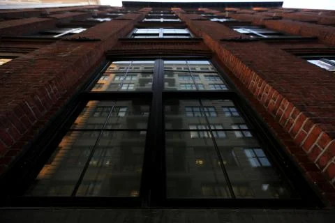 Bottom view of the building of brick which is connected by concrete with windows Stock Photos