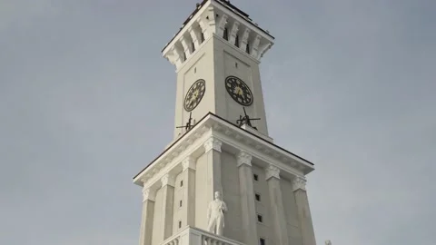 Bottom view of a clock tower with a long spire on blue cloudy sky background Vidéo 150258971