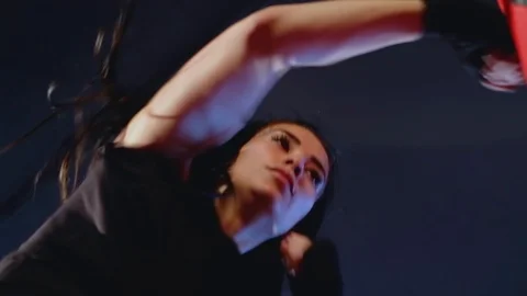 Bottom view, close-up cute brunette woman fulfills blows on punching bag in gym Stock Footage 93259698