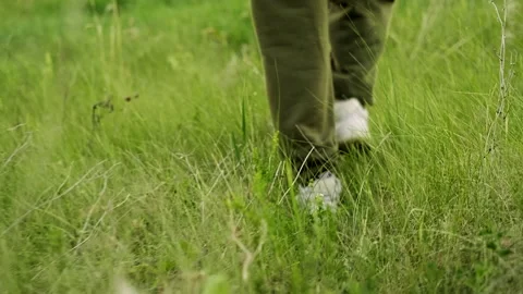 Bottom view. close-up of the legs of a guy walking on the dense green grass. out Stockbeeldmateriaal 162298343