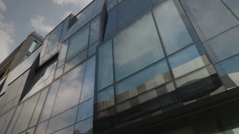 Bottom view on clouds reflected at large glass windows of modern office building Stock Footage 259310428
