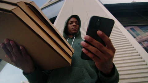 Bottom view of a delivery man with pizza boxes and a mobile phone outside Stock Footage 217363339