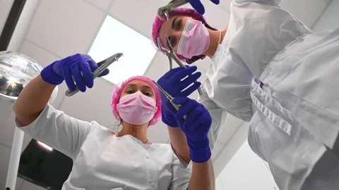 Bottom view dentist and assistant with sterile dental tools, lean toward patient Stock Footage 231009456