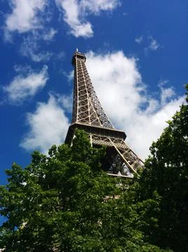 A bottom view of the Eiffel Tower against a cloudy sky on a sunny day in Pari Stock Photos