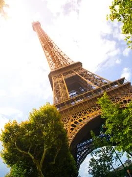 Bottom view of Eiffel Tower on sunny summer day, Paris, France. Sun leak effect Stock Photos