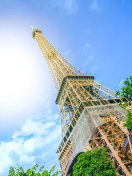 Bottom view of Eiffel Tower on sunny summer day, Paris, France. Sun leak effect Photos
