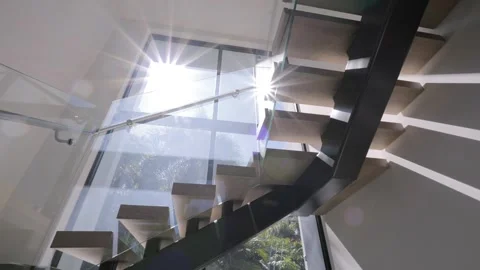 Bottom view of elegant staircase with glass railings inside building illuminated Stock Footage 262274604