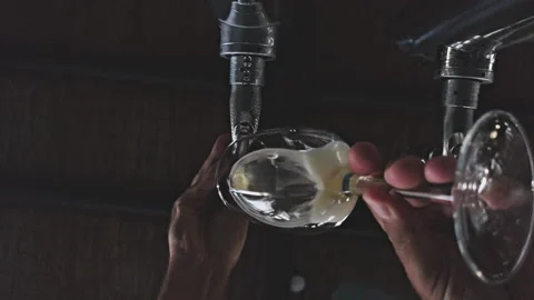 Bottom view of fresh beer pouring from dispenser into clear glass. Stock Footage 343940365
