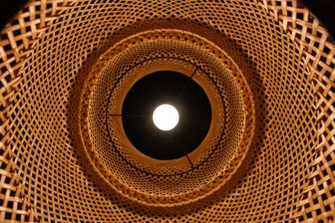Bottom view of glowing light bulb inside wicker bamboo lampshade geometric .. Stock Photos