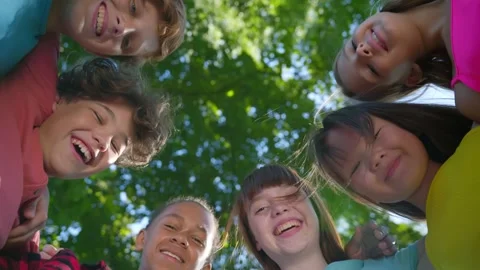 Bottom view of group of diverse children looking down into camera outdoors Vidéo 157962308