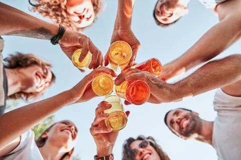 Bottom view of group of happy young people clinking bottles of beer Stock Photos