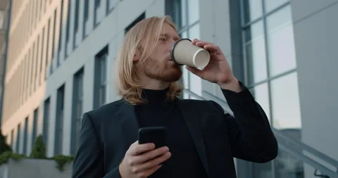 Bottom view of handsome businessman drinking coffee from paper cup and using Stock Footage 142679508