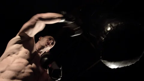 Bottom view of a man boxer beats a punching bag in boxing gloves Stock Footage 112946275