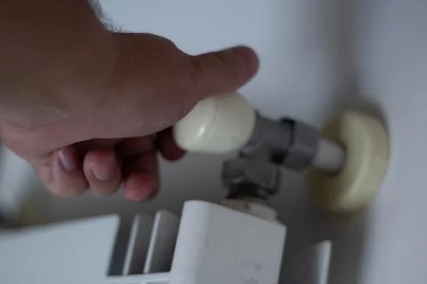 Bottom view. Man regulates temperature at home with knob on room battery Foto stock