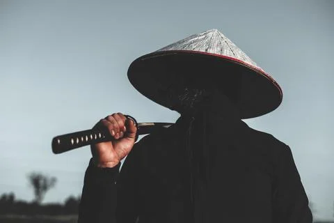 A bottom view of a masked samurai warrior holding a katana over his shoulde.. Stock Photos