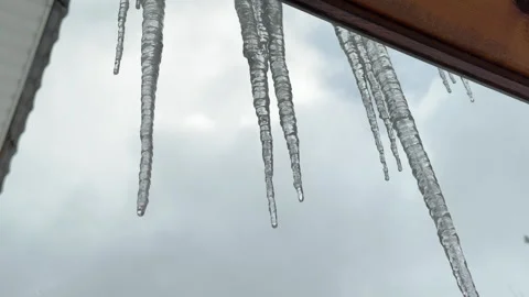 Bottom-up view of melting icicles against the gray sky in early spring Stock Footage 306258234