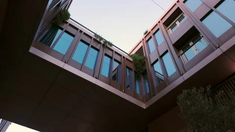 Bottom-up view of a modern building with a walkway and large floor-to-ceiling Stock Footage 289573736